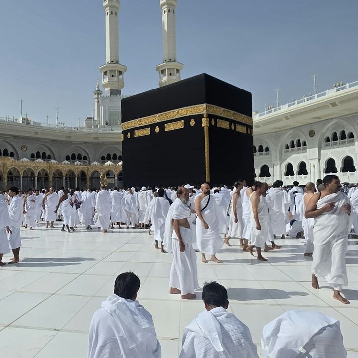Pilgrims in white ihram garments walking near the Kaaba in Mecca